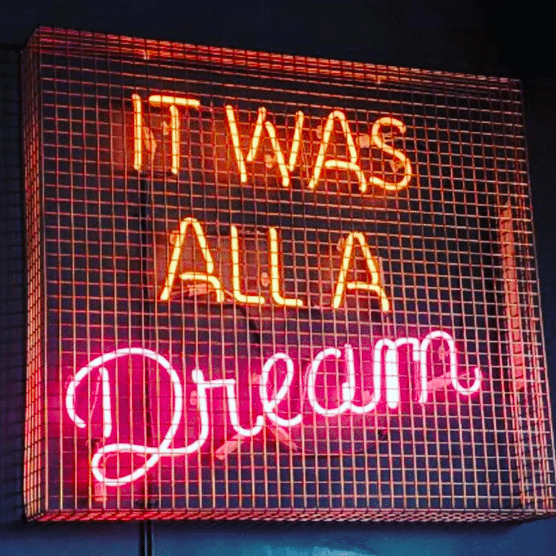 neon sign quotes - neon sign reading 'it was all a dream' in orange and pink neon behind a cage 