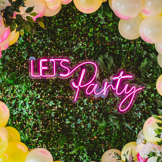 party neon sign - pink led neon let's party sign fixed to a green living wall 