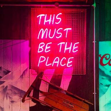 Music Neon Sign Quotes - Pink caged neon sign showing the lyrics 'This Must Be The Place' by Talking Heads